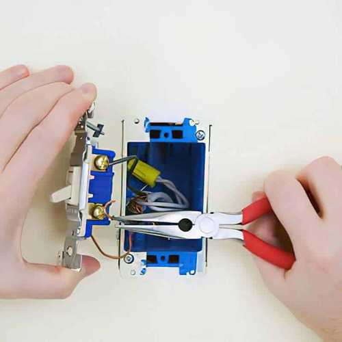 An Electrician Repairs an Electrical Outlet.